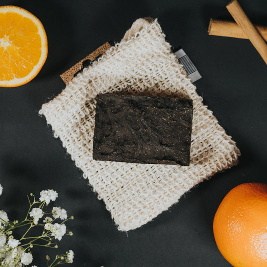 An environmentally friendly FLON black soap with oranges and cinnamon on a Natural Sisal Washcloth.