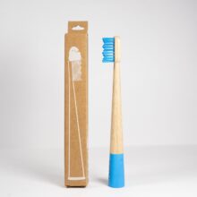 Description: A blue FLON Kids Bamboo Toothbrushes next to a cardboard box, ideal for travel and storage.