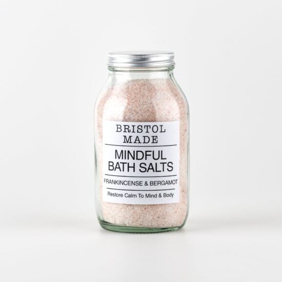 photo of a clear glass jar filled with pale pink bath salts, jar has a white label with black text showing the essential oils in the salts