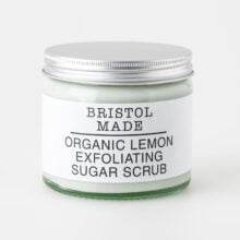 image of a Bristolmade body scrub, highlighting its rich ingredients and exfoliating particles. Packed in an eco friendly, 250ml clear glass jar, with a clear label detailing its rejuvenating and nourishing properties.