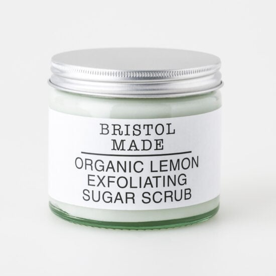 image of a Bristolmade body scrub, highlighting its rich ingredients and exfoliating particles. Packed in an eco friendly, 250ml clear glass jar, with a clear label detailing its rejuvenating and nourishing properties.