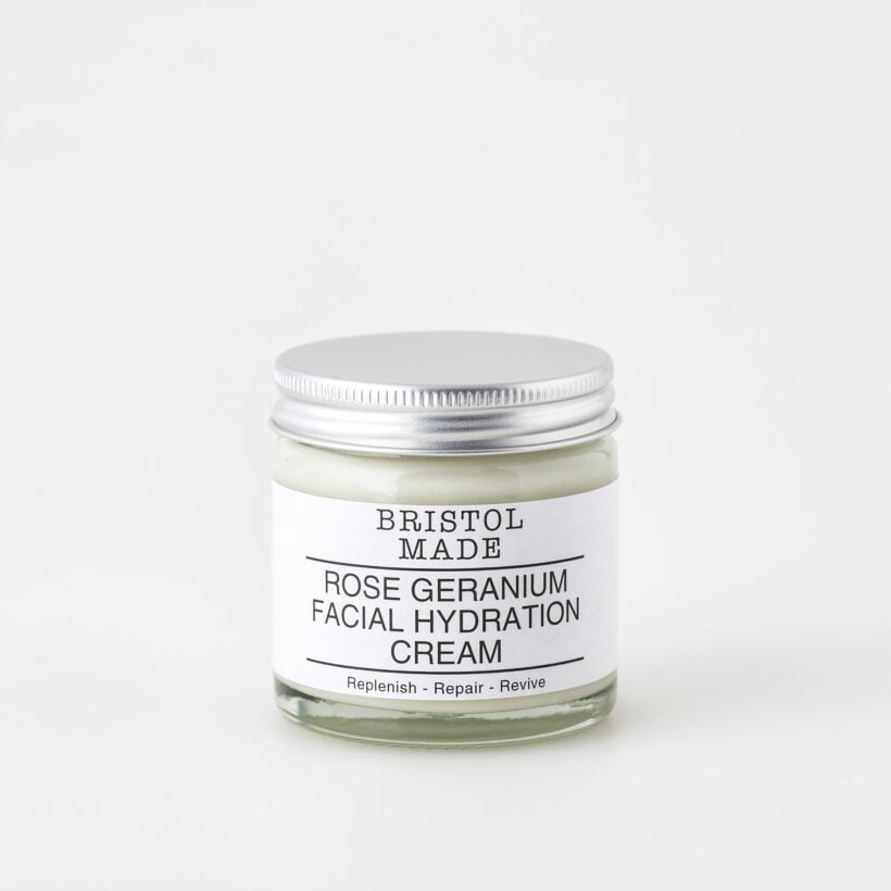 A 60ml clear glass jar of Bristolmade rose geranium face cream, featuring a white label with black text, highlighting its vegan ingredients.