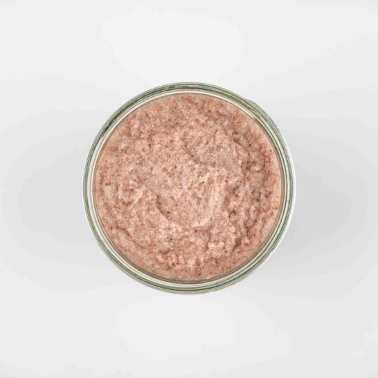 top view of a pale pinky body scrub, showing the exfoliating texture of the salt in the scrub.