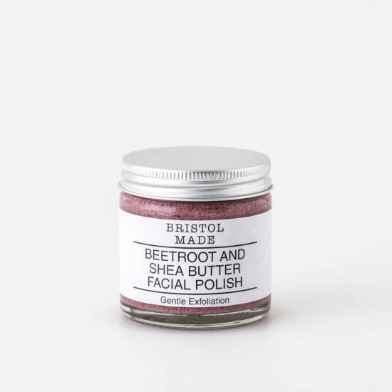 Photo of Bristolmade exfoliating face scrub, showing the pink blend of natural ingredients and gentle exfoliating particles. Packaged in a 60ml clear glass jar, with a white label, clearly indicating the products purpose and benefits.