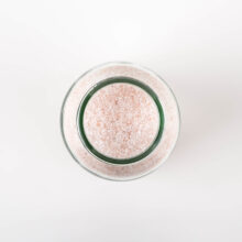 top view of a jar of bath salts, showing the pale pink granules of the epsom salts