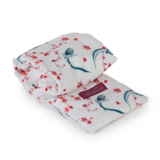 photo of a rolled up lavender wheat bag, showing the white main fabric with pale blue birds and small pink and cream flowers