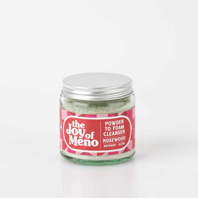 photo of a 120ml clear glass jar, containing a pale green powder cleanser, with a pink patterned label with white text.