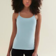 Woman wearing a light blue sustainable Pilates tank top and black yoga shorts made from sustainable, GOTS certified organic cotton and biodegradable elastane by Wellicious, perfect for eco-friendly activewear.