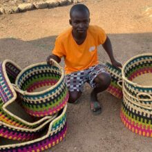 Ghanaian weaver from Bolgatanga sitting next to the baskets he has made