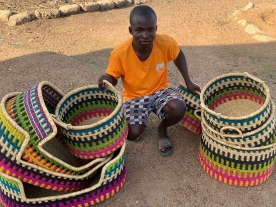 Ghanaian weaver from Bolgatanga sitting next to the baskets he has made