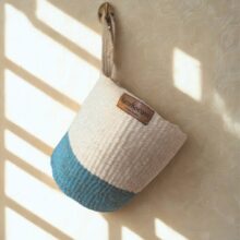 Hanging baskets_Karakorum (4) natural Handwoven sisal hanging baskets with block of indigo colour at the base with twist handles - hanging on brass hooks in soft daylight.