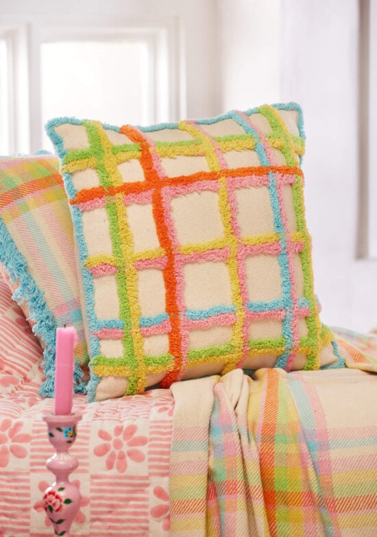 Handmade tufted check cushion cover in multicolour on a natural recycled cotton base, with tufted grid pattern in orange, pink, yellow, green and blue, finished with a blue tufted border. 45x45cm.